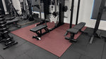 Red rubber gym flooring tiles installed in a home gym with commercial fitness equipment