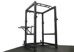 ['Elite Commercial Power Rack front view', 'Power rack with multi-grip pull-up bar', 'Heavy-duty J-hooks and safety bars', 'Adjustable tricep dip station included', 'Full rack setup in home gym environment']